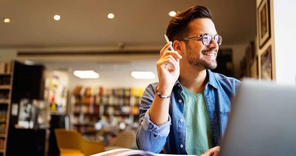 University student studying online with pen in hand